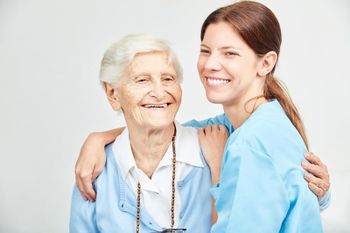 Krankenpflegerin umarmt Rentnerin