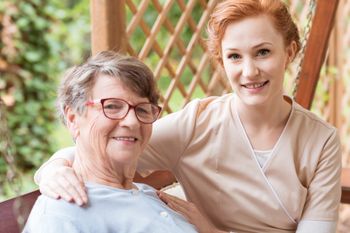 Krankenpflegerin umarmt Rentnerin